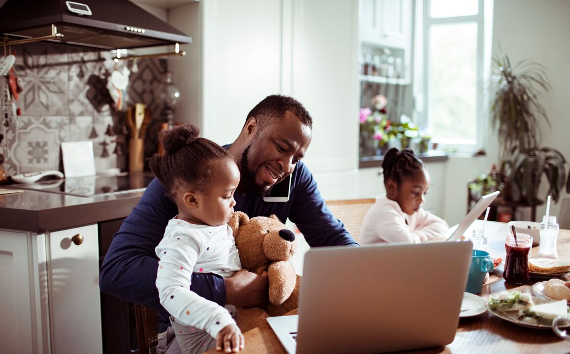 Man on the phone with two children while looking at laptop